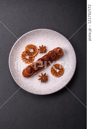 Sweet eclair with chocolate custard sprinkled with cocoa powder 121782572