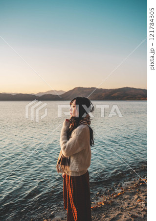 夕方の湖とニットとマフラーの若い女性 121784305