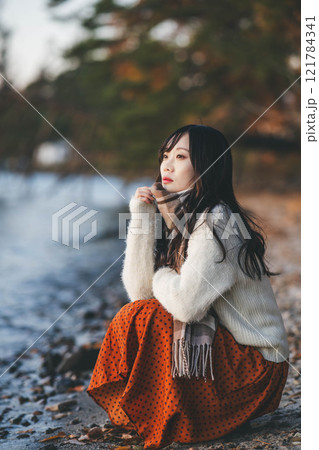 夕方の湖とニットとマフラーの若い女性 121784341