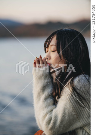 夕方の湖とニットとマフラーの若い女性 121784359