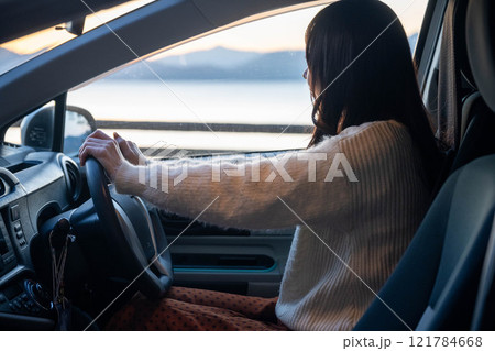車の運転をするロングヘアの若い女性 121784668