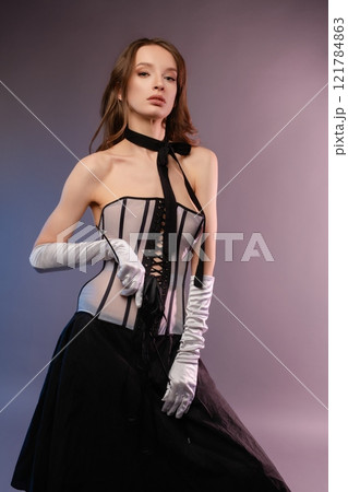 Elegant woman in corset and gloves poses stylishly for modern fashion shoot Elegant woman in corset and gloves poses stylishly for modern fashion shoot 121784863