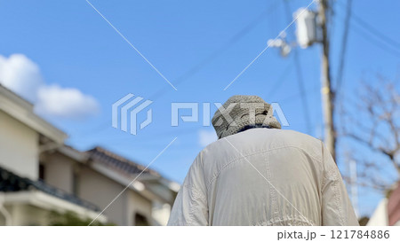 青空の下の住宅地を歩く高齢女性の後姿 121784886