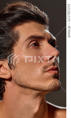 Side profile of man's face with well-kept, smooth, radiant skin. Model looking upwards with calm expression, showing defined jawline and neatly groomed hair. Side profile of man's face with well-kept, smooth, radiant skin. Model looking upwards with calm expression, showing defined jawline and neatly groomed hair. 121785153
