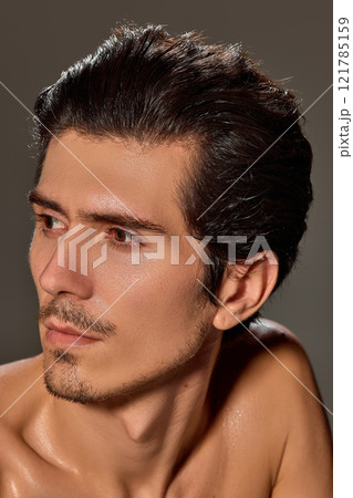 Close-up side profile of man with serene expression. His smooth skin and sharp jawline highlighted against dark background. Close-up side profile of man with serene expression. His smooth skin and sharp jawline highlighted against dark background. 121785159