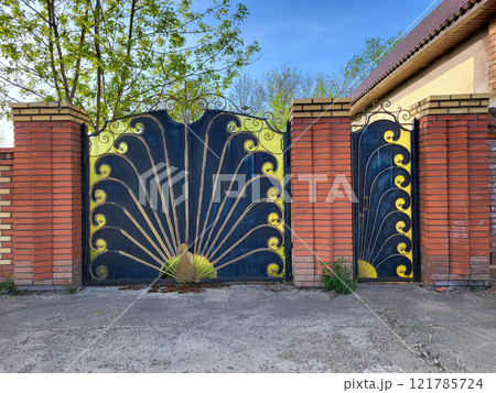 Wrought iron gates in the shape of a peacock with red brick columns. Wrought iron gates in the shape of a peacock with red brick columns. 121785724