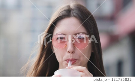 Pensive happy woman sipping a milkshake in the street Pensive happy woman sipping a milkshake in the street 121785823