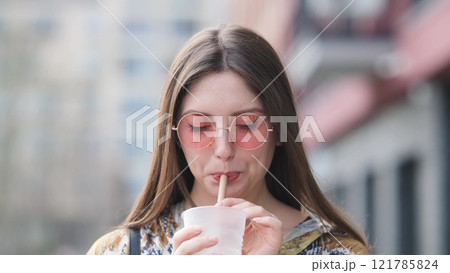 Pensive happy woman sipping a milkshake in the street 121785824