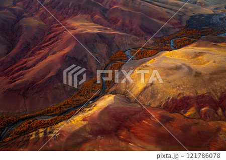 Aerial view of vibrant red mountains and winding river in autumn landscape Aerial view of vibrant red mountains and winding river in autumn landscape 121786078