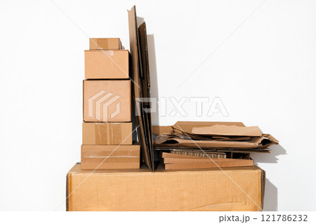 Creative minimalist image of stacked cardboard boxes and flattened on a plain background, representing concepts of recycling, moving, storage, shipping, and organization 121786232