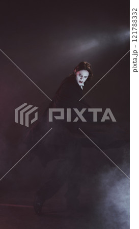 Man with pale face and cape, looks as vampire, spins dramatically, shows terrifying sharp fangs, in dimly lit setting. 121788332