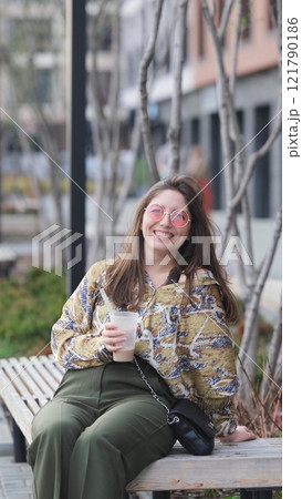 Pensive happy woman sipping a milkshake in the street 121790186
