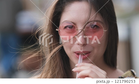 Pensive happy woman sipping a milkshake in the street 121790253