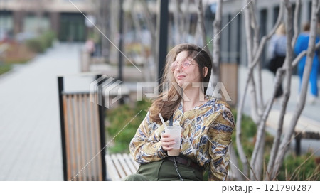 Pensive happy woman sipping a milkshake in the street 121790287
