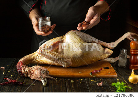 A chef adds aromatic dry spices to a raw turkey carcass. An idea for preparing a tasty bird for a hotel or restaurant dinner A chef adds aromatic dry spices to a raw turkey carcass. An idea for preparing a tasty bird for a hotel or restaurant dinner 121790390