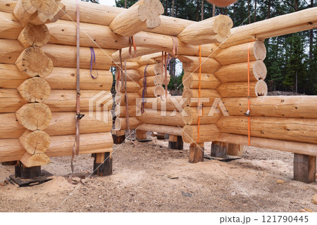The construction site of a wooden house. Traditional log cabin built from wood logs on sunny summer day. Cottage house design 121790445