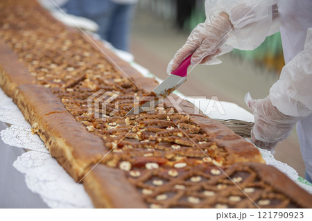 A chef's knife cuts yeast pies on an industrial tape. A chef's knife cuts yeast pies on an industrial tape. 121790923