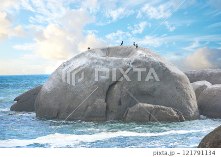 Scenic view of a beach with rocks or boulders and sea water. The landscape of a rocky coastline in spring. A big rock in the middle of the ocean with birds on it and blue sky background in summer. Scenic view of a beach with rocks or boulders and sea water. The landscape of a rocky coastline in spring. A big rock in the middle of the ocean with birds on it and blue sky background in summer. 121791134