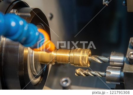 Close up scene multi-tasking CNC lathe machine swiss type hole drilling process the brass coupling parts. 121791308