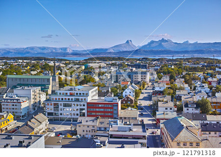Aerial view of Bodo city in Norway on a sunny day with a blue sky. Scenic modern urban landscape of streets and buildings near a mountain horizon with copy space. Peaceful rural town from above 121791318