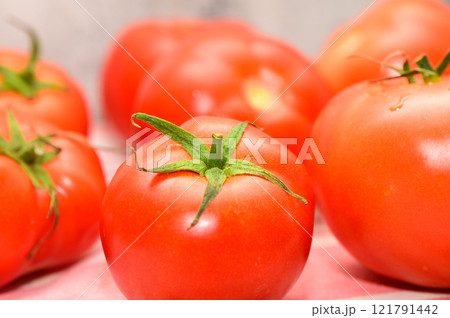 Vibrant red tomatoes arranged artistically on a textured surface, showcasing fresh produce in natural light 121791442