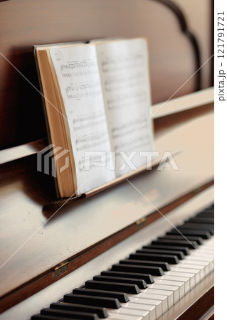 Closeup of a vintage piano and keyboard with a sheet music book. An empty antique or wooden musical instrument for playing classical jazz or used for old traditional songwriting and rehearsals 121791721