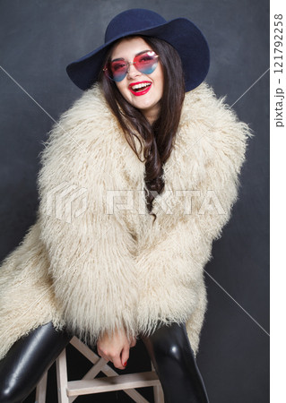 Laughing woman with red lips make-up and long wavy hair wearing blue hat Laughing woman with red lips make-up and long wavy hair wearing blue hat 121792258