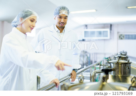 Team of quality control officers or factory engineers are inspecting inside the beverage manufacturing facility. Man and woman engineers working in a food production factory. Team of quality control officers or factory engineers are inspecting inside the beverage manufacturing facility. Man and woman engineers working in a food production factory. 121793169