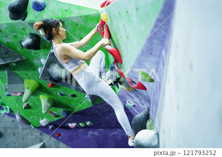 Asian sportswoman practices an indoor rock climbing wall. 121793252