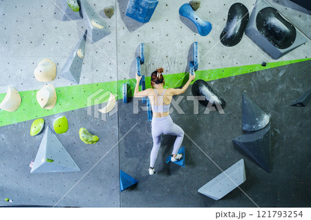 Asian sportswoman practices an indoor rock climbing wall. 121793254