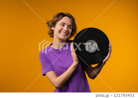 Pretty woman dancing with vinyl record disc on yellow. Hobby, music lover, collection, nostalgia lifestyle. 121793451