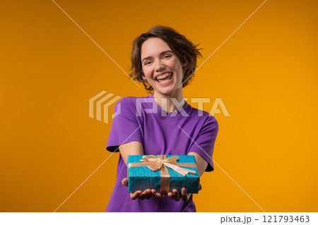 Happy charming woman gift box on yellow background. Young girl smiling,gives you Happy charming woman gift box on yellow background. Young girl smiling,gives you 121793463