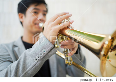 Asian man plays cornet. A solo Asian skillful musician is playing or practicing cornet in the restaurant. A man enjoy playing cornet or trumpet. 121793645