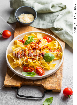 Tagliatelle pasta with tomato sauce, basil and parmesan cheese in a plate on a wooden board 121794877