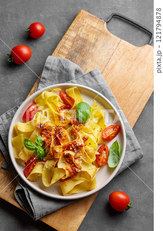 Tagliatelle pasta with tomato sauce, basil and parmesan cheese in a plate on a wooden board 121794878