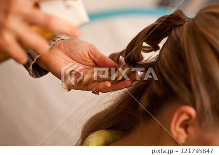 A Hair Styling Session is Underway Featuring Elegant Twists and Beautiful Curls A Hair Styling Session is Underway Featuring Elegant Twists and Beautiful Curls 121795847