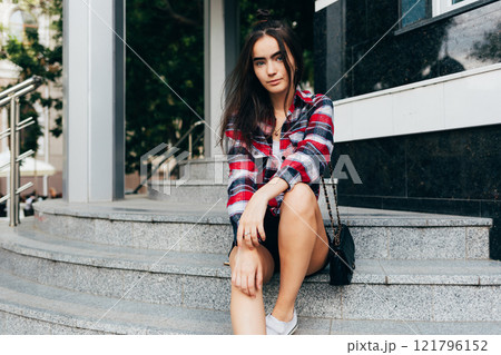 A woman is sitting on a set of stairs 121796152