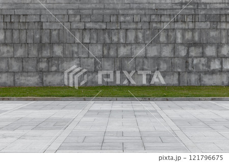 Urban background texture with gray stone wall and green grass 121796675