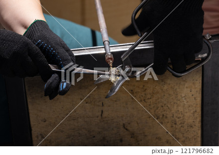 Molten glass sculpting, works of a  glass blowing workshop in progress 121796682
