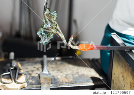 Sculpting of a flower made of molten glass. Glass blowing workshop Sculpting of a flower made of molten glass. Glass blowing workshop 121796697