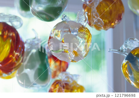 Colorful glass decoration hanging in front of bright window, close-up Colorful glass decoration hanging in front of bright window, close-up 121796698