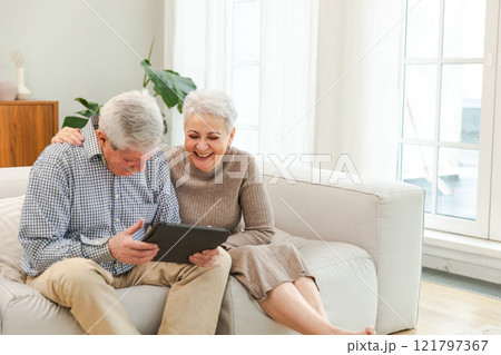 Senior old couple with tablet watching video online. Husband wife spending time together at home. Happy modern mature senior couple using tablet for family entertainment. Old people modern technology Senior old couple with tablet watching video online. Husband wife spending time together at home. Happy modern mature senior couple using tablet for family entertainment. Old people modern technology 121797367