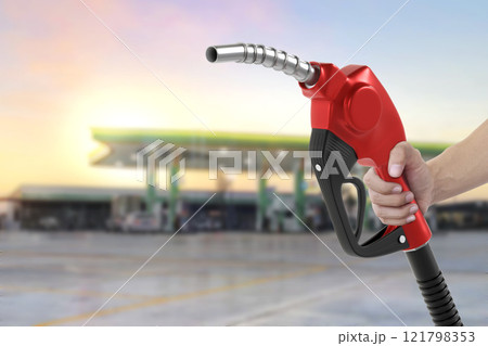 Holding a fuel nozzle against with gas station blurred background 121798353
