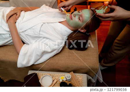 Woman indulges in rejuvenating with luxurious face cream spa massage. Quiescent Woman indulges in rejuvenating with luxurious face cream spa massage. Quiescent 121799036