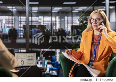 Female boss discussing about tasks on a phone call during problem solving meeting, contacting employees via mobile phone call. CEO discussing about latest project developments. Female boss discussing about tasks on a phone call during problem solving meeting, contacting employees via mobile phone call. CEO discussing about latest project developments. 121799668