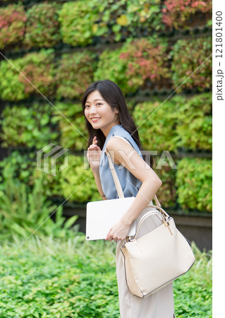 壁面緑化されたビルの前でタブレットを持つビジネスウーマン 121801400