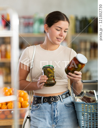 Young woman chooses pickled cucumbers and tomatoes Young woman chooses pickled cucumbers and tomatoes 121802730
