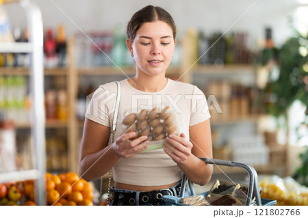 Young woman holding plastic containers with champignons, choose mushrooms. 121802766