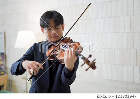 Solo classical musician is playing viola. A solo Asian young professional musician is playing or practicing a viola alone at home. Skillful classical musician plays a viola or violin. Solo classical musician is playing viola. A solo Asian young professional musician is playing or practicing a viola alone at home. Skillful classical musician plays a viola or violin. 121802947