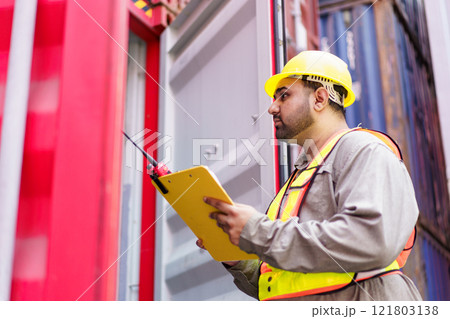 Asian male logistic worker in safety workwear portrait at the container yard. Logistic foreman portrait. Male logistic supervisor is inspecting the incoming cargo container at container yard. Asian male logistic worker in safety workwear portrait at the container yard. Logistic foreman portrait. Male logistic supervisor is inspecting the incoming cargo container at container yard. 121803138